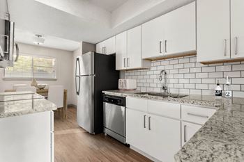 a kitchen with white cabinets and a stainless steel refrigerator at South Lamar Village, Austin, TX
